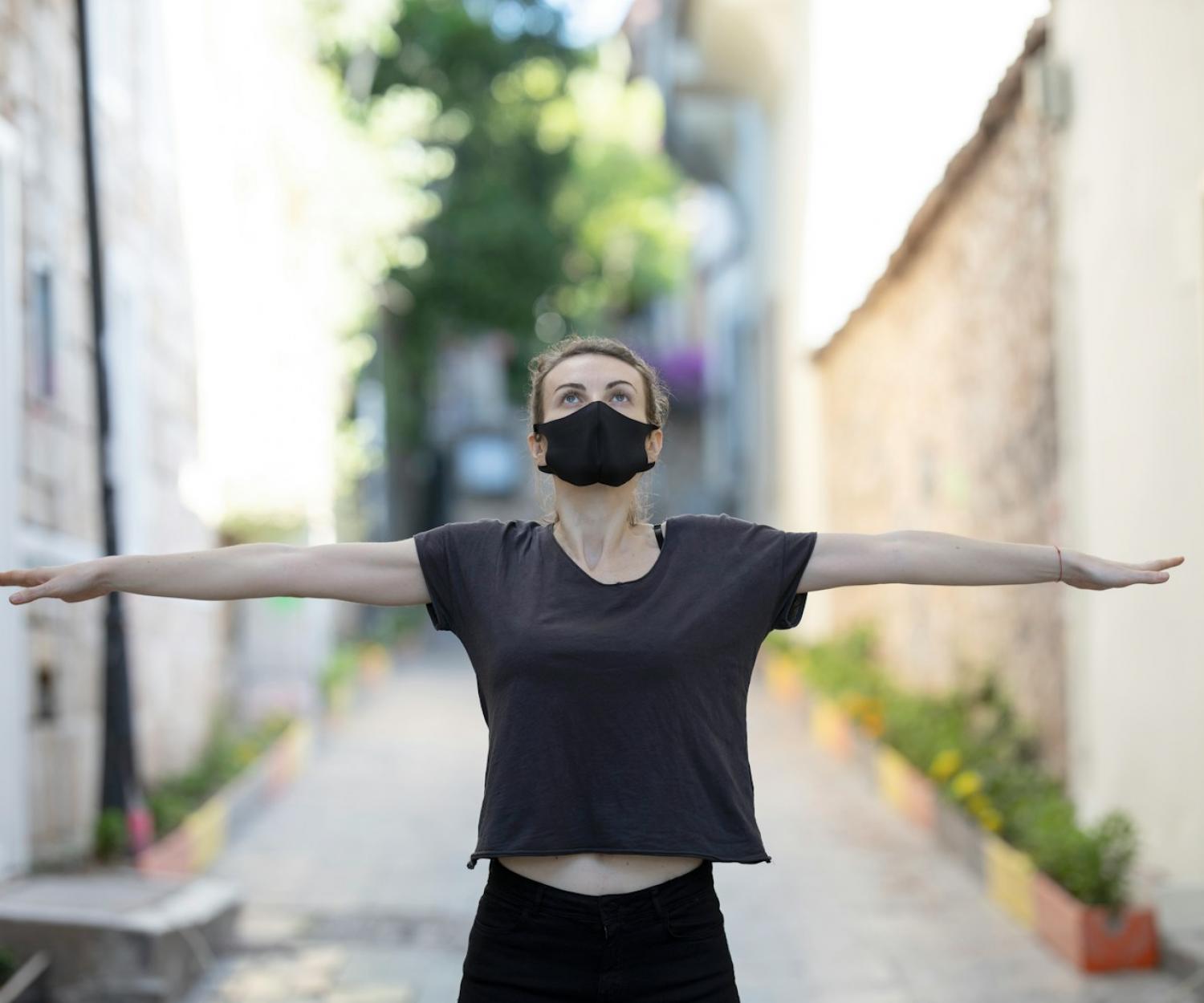 WELL woman in black t-shirt and black shorts raising her hands